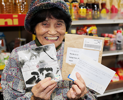 香港から届いた礼状とハンカチを手に笑顔の今井奈智子さん