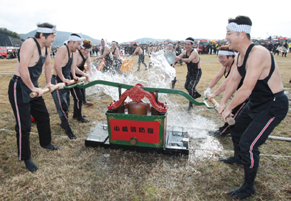 放水合戦で手漕ぎポンプを動かす消防団員