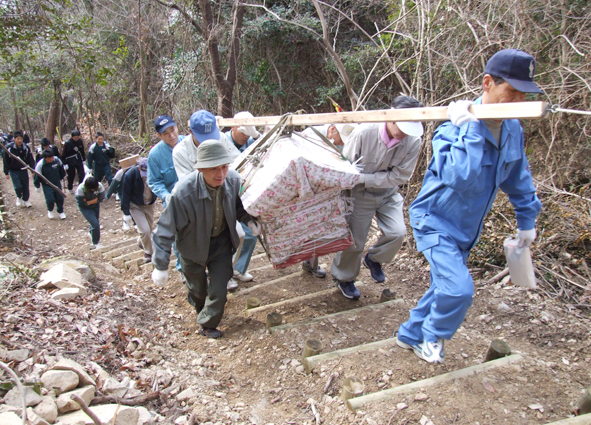 「登山記録台」を担いで上がる同自治会の人たち