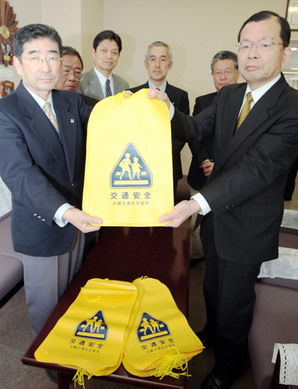 宮本邦夫・教育長(右)にランドセルカバーを贈呈する関孝行会長