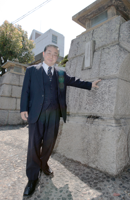 橋本博行・第23代校長。赤穂城跡から移築の旧校舎正門に「思い出深いですね」