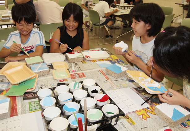 8月のキャンプに向けてレンガに色を塗る子どもたち