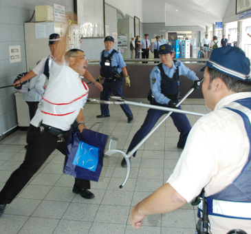 防犯訓練で、刃物を振り回して抵抗する「通り魔犯」を追い詰める警察官