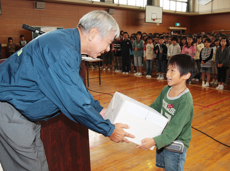 山之口敏雄・赤穂ライオンズクラブ会長から補聴器を受け取る小野颯太君