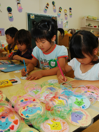手作りペンダントにメッセージを書き入れる子どもたち