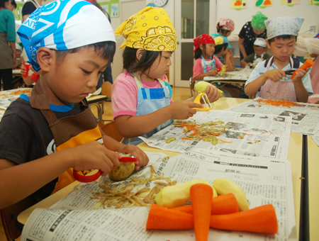 真剣な表情で野菜の皮をむく園児たち