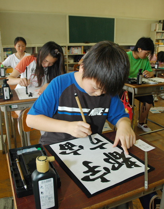 真剣な表情で筆を動かす参加者ら