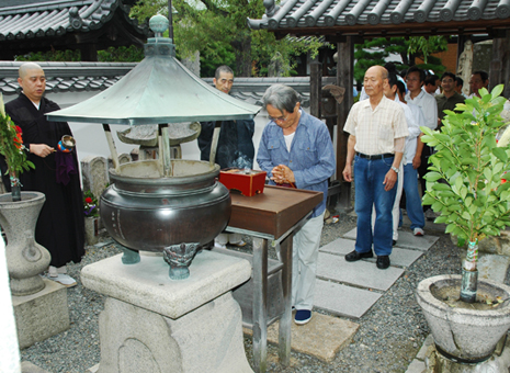清掃後、義士墓所で手を合わせるロータリー会員=花岳寺