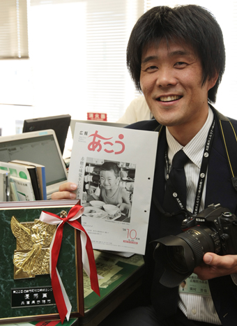 優秀賞の「広報あこう」を手に喜びを語る廣村晋也係長