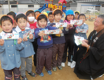 霜尾孝紹住職から影絵劇のチケットを手渡された久崎保育園の子どもたち