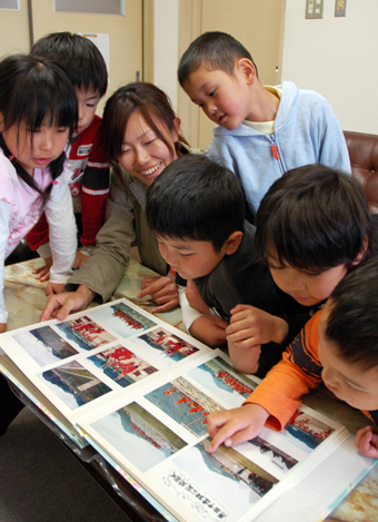 15年前の開園式を教え子たちにアルバムで見せる起塚裕子教諭