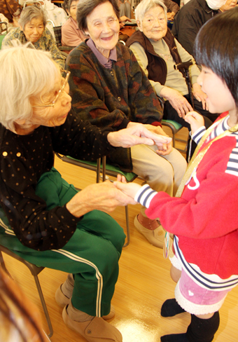 交流会で手を取り合う入所者と園児