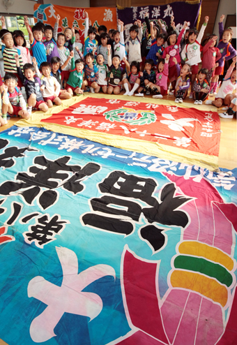 被災地から送られた大漁旗へ向かって「がんばろう日本!」と声を合わせた子どもたち=塩屋幼稚園