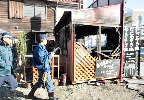 全焼した店舗を現場検証する捜査員