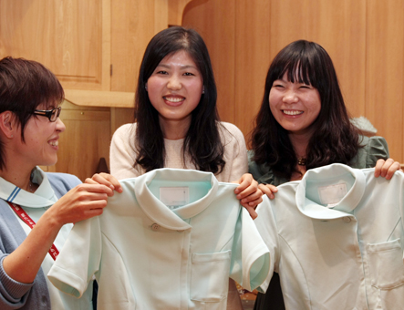 あこがれのナース服を手に国家試験合格を祝福される陳偉さん(中)と王セイさん(右)