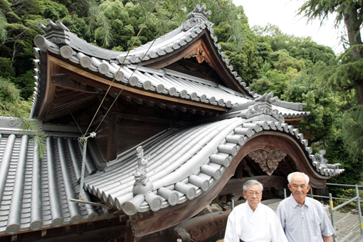 瓦を92年ぶりに全面的に葺き替えた荒神社の社殿。大嶋宮司(左)と綿田総代会長