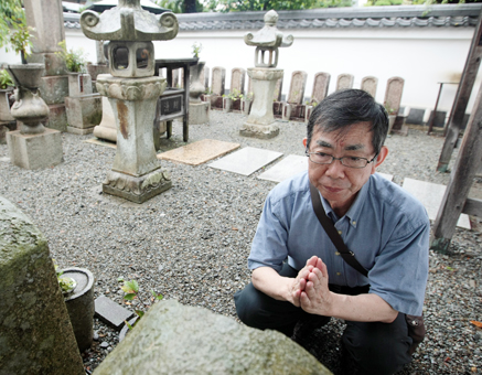 花岳寺の義士墓所で寺坂吉右衛門の墓石に手を合わせる金子明さん