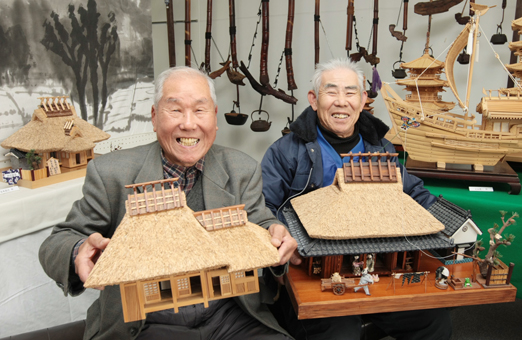 幼なじみ同士でミニチュア作品展を開いている谷本昌己さん(右)と上山長一さん
