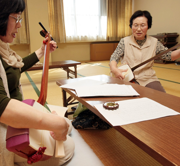 「曳きとんど音頭」の採譜に取り組む佐方さよ子さん(右)と牟禮清美さん