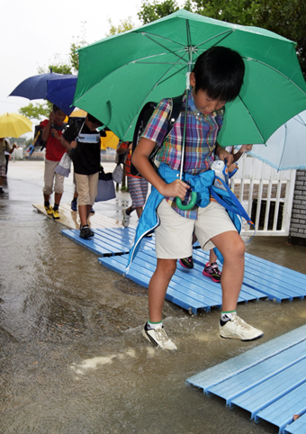学校から早退する児童たち。校門には大雨で水たまりができていた=9月4日午前10時12分撮影
