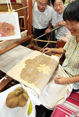 「ひょんの実」=手前=を染料に使った赤穂緞通に取り組む=右から=根来節子さん、小田中久良子さん、田川芳弘さん
