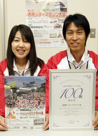 「全日本ランニング大会100撰」の認定書と大会要項を手に第4回赤穂シティマラソンをPRする実行委事務局スタッフ