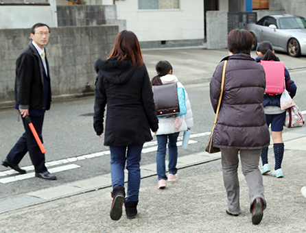 職員が見守る中、保護者に付き添われて下校する児童=尾崎小