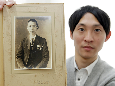 80年以上前に赤穂市内の写真館で撮影された一枚を手に情報提供を呼び掛ける下村貴之さん