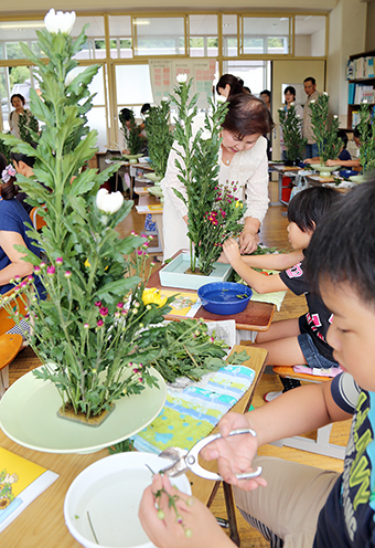 真剣な表情で生け花を体験する児童たち