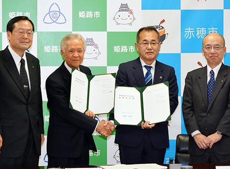 赤穂、姫路両市長が握手を交わした協約調印式=赤穂市提供