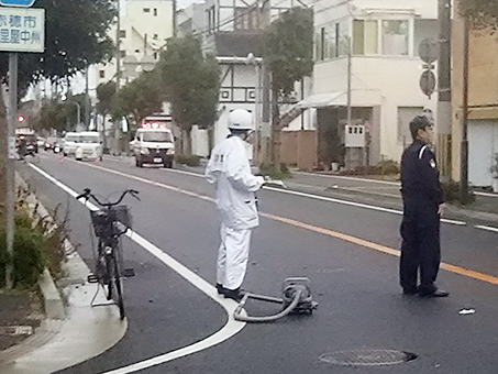 ひき逃げ事件の発生現場で遺留品を調べる捜査員。男性が乗っていた自転車が残っていた=3月18日午後5時45分ごろ撮影