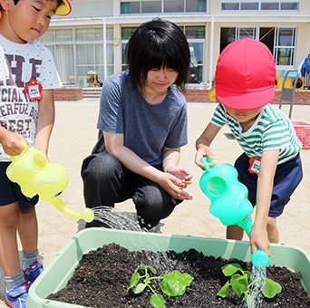 ひょうたんを植えたプランターに水やりする子どもたち
