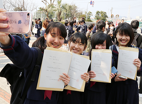 合格証を手に友人同士で記念写真を撮る受験生たち