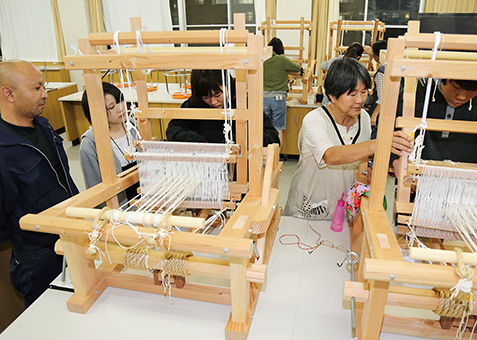OBの茶谷誠さん=左端=がつくった小型織機で行われている赤穂緞通製作体験