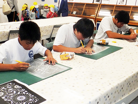 形紙の復刻作業で文様を切り抜く中学生=同館提供