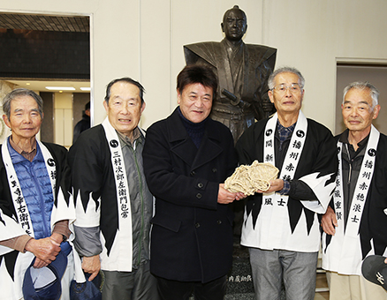 「手作り文化伝承の会」からわらじを贈られた柴田善明さん=中央。今回で41年連続の義士祭見物となった