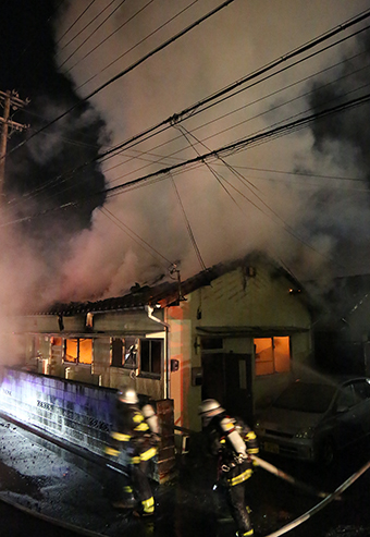 白煙が上がる民家へ消火活動へ向かう消防隊員=1月30日午後8時31分