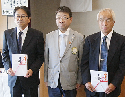 木虎知己会長(中)から2自治会に目録を渡した防犯カメラ贈呈式