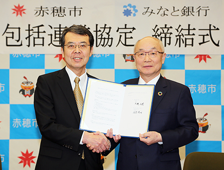 包括連携協定を締結して握手を交わす牟禮正稔市長と服部博明頭取(右)