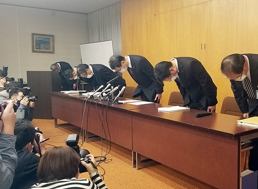 市職員逮捕を受けて行われた記者会見で頭を下げる幹部職員