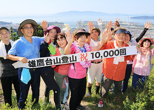 雄鷹台山で初の通算1万日登山を達成し、仲間から祝福される常念初恵さん=中央